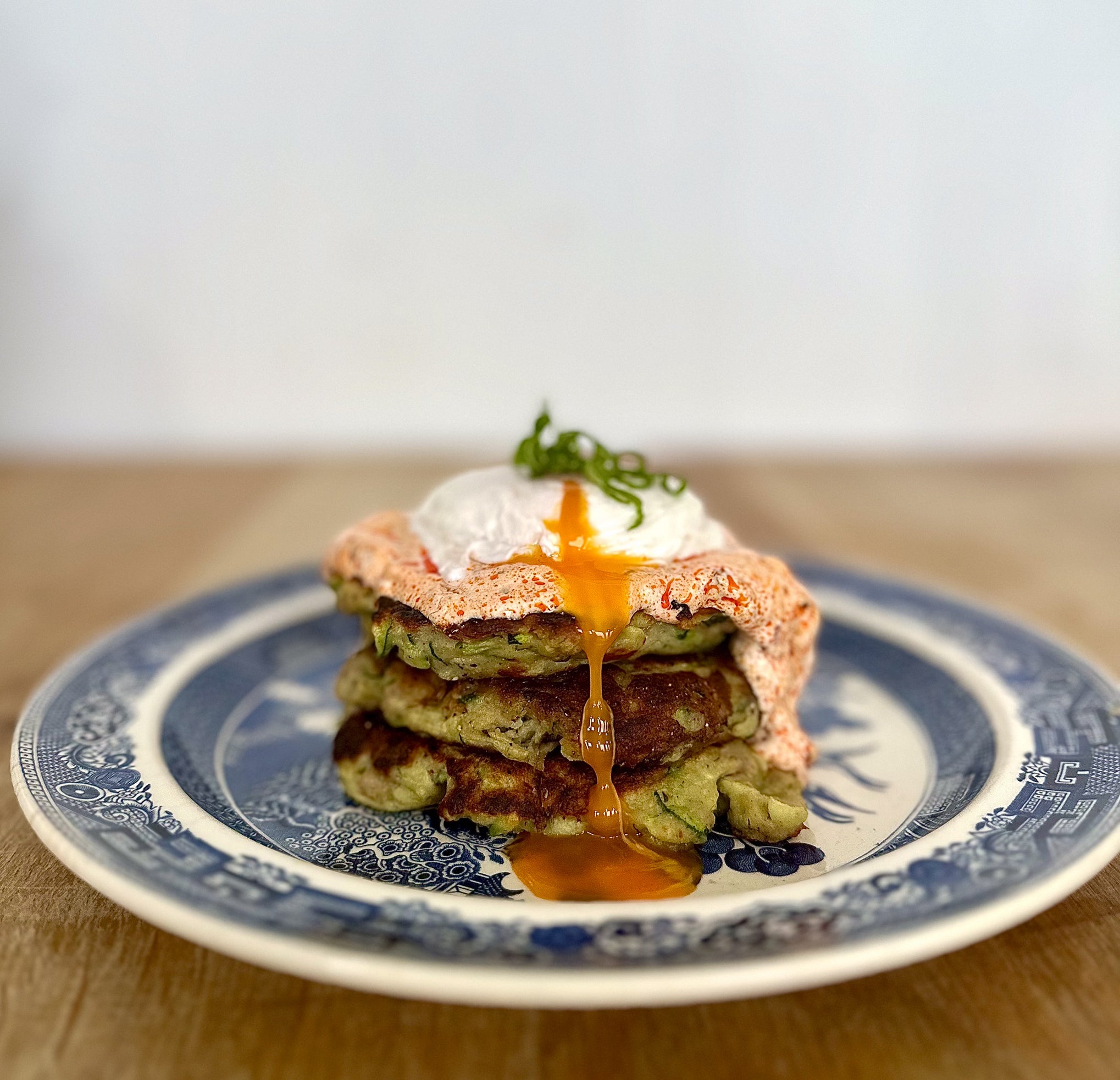Sausage and courgette ricotta pancakes, poached eggs, harissa yogurt b ...