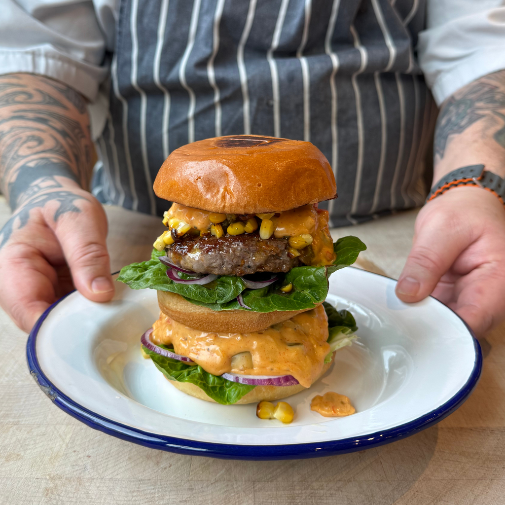 Double Stack Maverick Burger with queso, charred corn salsa, onion & tomato by Matt Burgess