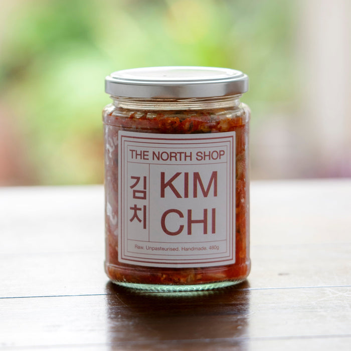 Jar of kimchi from The North Shop on a wooden surface with a blurred natural background